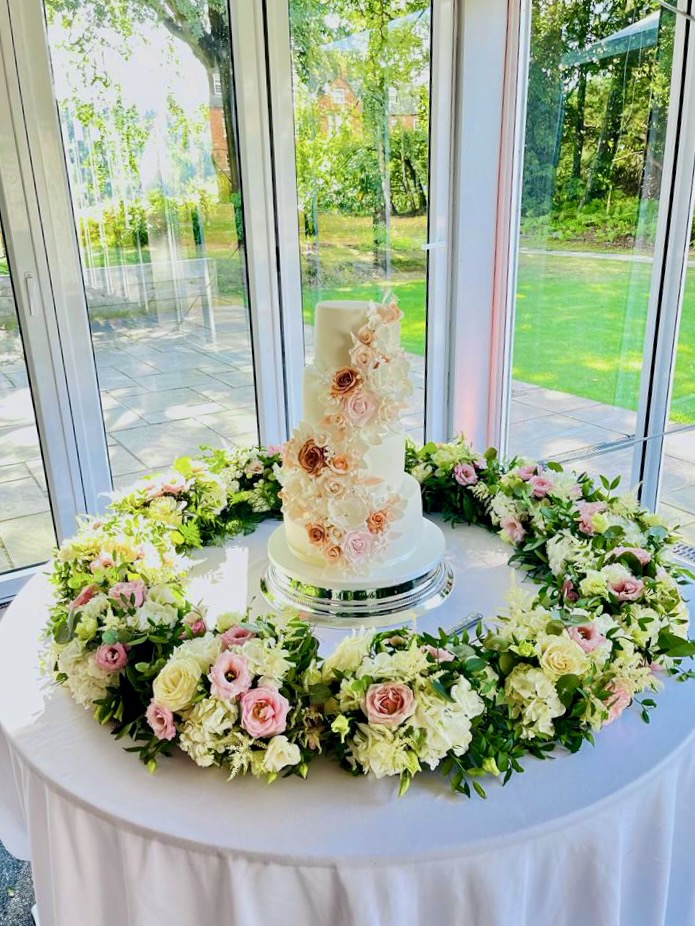 Statement Round Arrangement of Flowers Surrounding Wedding Cake