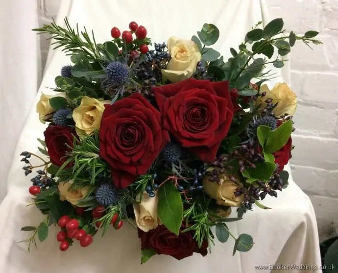 Christmas wedding bridal bouquet of red and sandy roses, eryngium, viburnum berries, hypericum berries, rosemary and eucalyptus