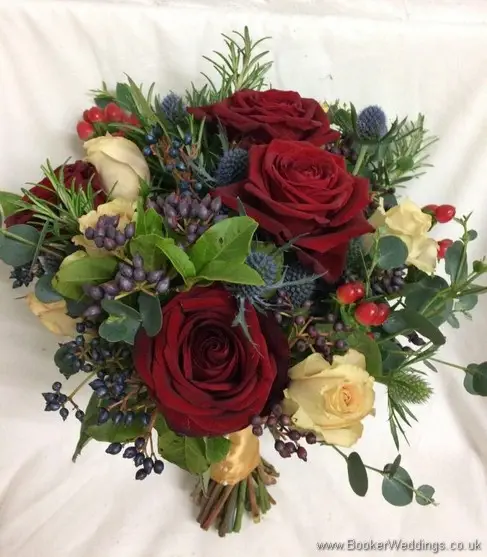 Semi-wild winter wedding bridal bouquet of red and sandy roses, eryngium, viburnum berries, hypericum berries, rosemary and eucalyptus