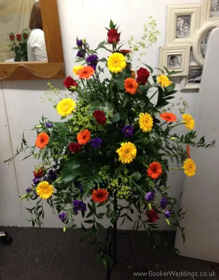 Bright and vibrant large pedestal arrangement for the church featuring roses, gerberas, lissianthus and alchamelia molis