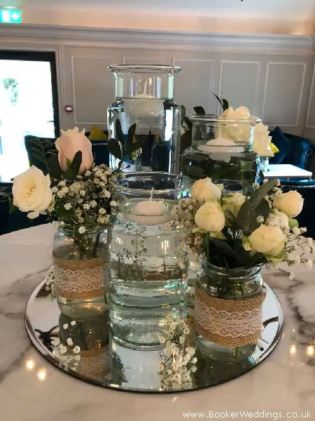Table Arrangement of Glass Vases Mirror Plates and Roses