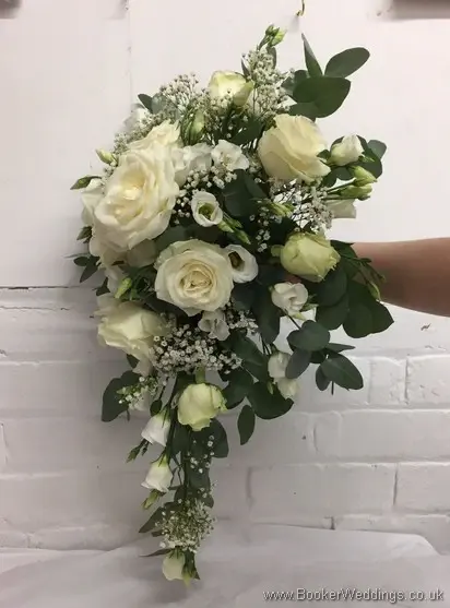All white shower bouquet with eucalyptus foliage featuring roses, gypsy grass and lissianthus left side