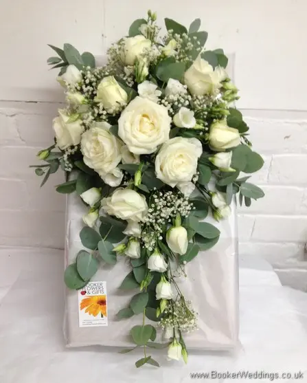 All white shower bouquet with eucalyptus foliage featuring roses, gypsy grass and lissianthus