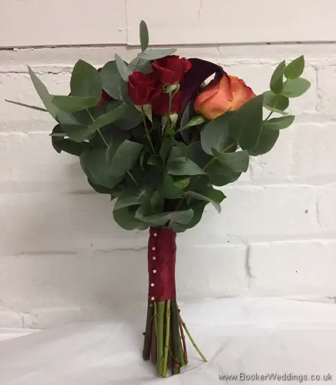 Handtied bridesmaid orange, raspberry & dark red coloured bouquet with roses, spray roses and calla lillies side view