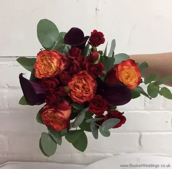 Handtied bridesmaid orange, raspberry & dark red coloured bouquet with roses, spray roses and calla lillies
