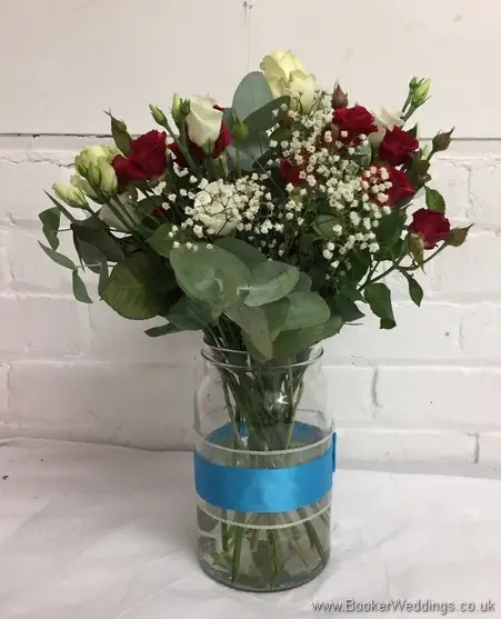 Top table arrangment of white and red flowers, including roses, spray roses, lissianthus and gypsophila side view