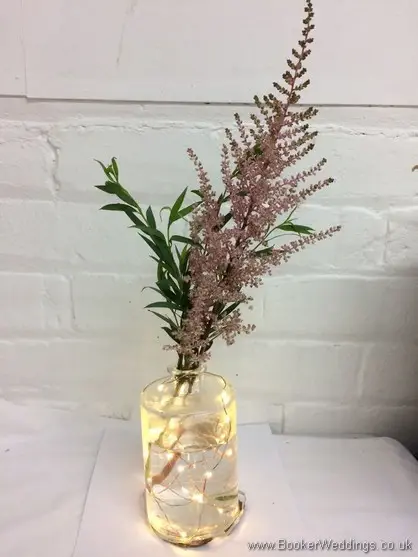 Pink astilbe in a lit up bottle table centrepiece