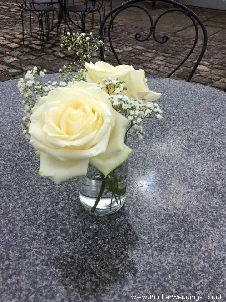 Wedding venue table centerpiece of roses and gyp in jars
