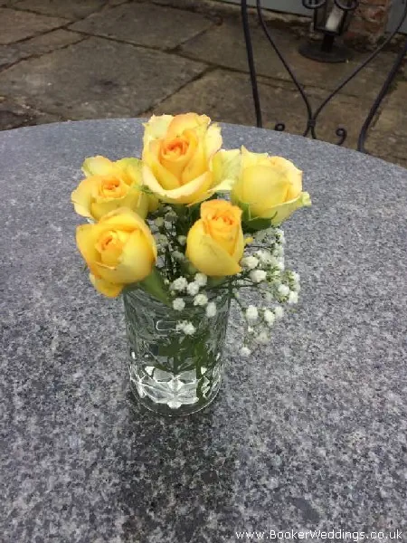 Wedding venue table centerpiece of spray roses and gypsy grass in jars
