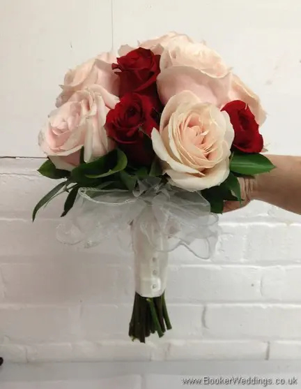 Bridal hand-tied bouquet featuring red and soft pink roses with a white organza bow side view