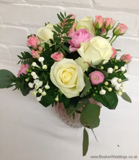 Semi-wild pale pink and cream wedding reception table centrepieces in vases with roses, ranunculus, bouvardia, spray roses and eucalyptus