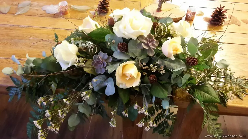 Winter woodland themed wedding Top Table Arrangement with Cream avalanche & peach roses, burgundy succulents, copper cones & twigs