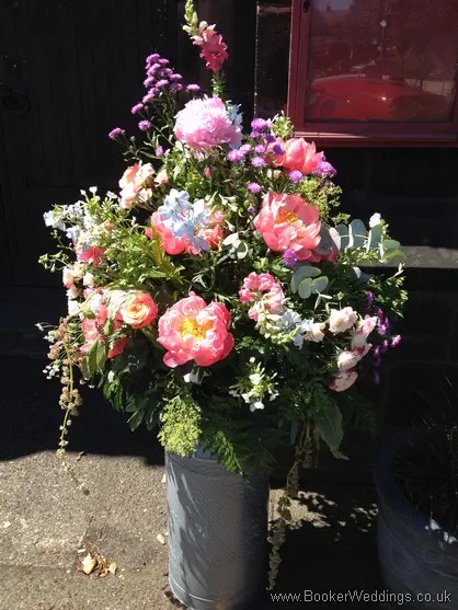 Large bright colourful just picked country style milk churn arrangement for entrance to St Barnabus Church, Liverpool