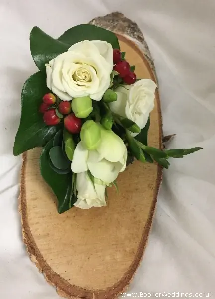 Winter theme wedding corsage of ivory roses freesia red hypericum berries and eucalyptus