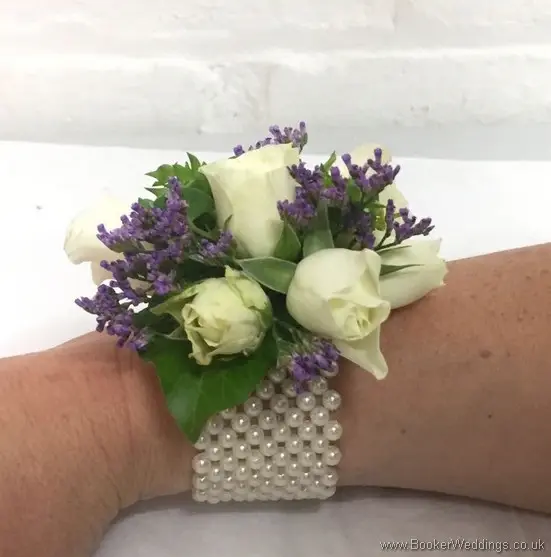 White and purple wrist corsage with white spray roses and purple limoneum side view with a pearl bracelet