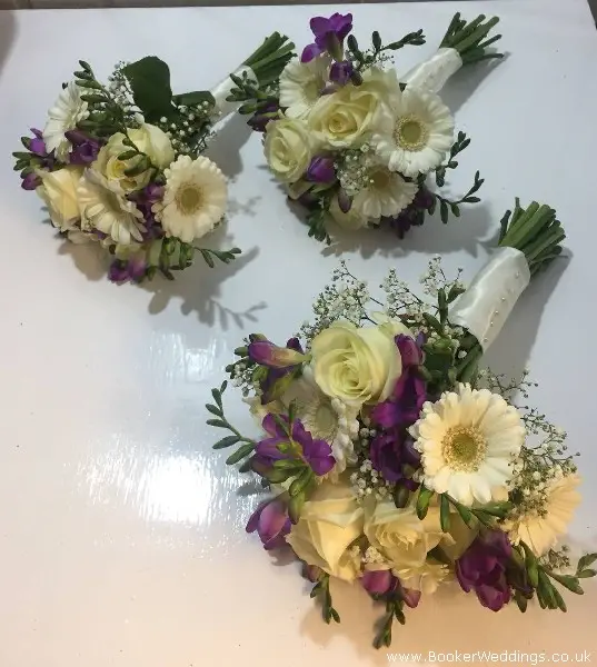 bride and bridesmaids handtied bouquets white gerberas white roses purple freesia and gypsophila