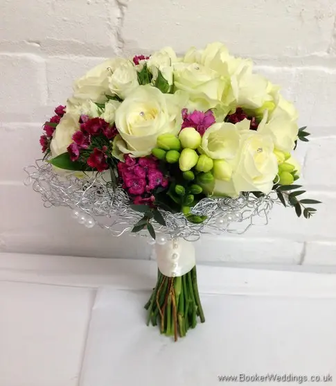 Bridal hand tied bouquet featuring Roses and Spray Roses, Freesia and Sweet William caged in silver wire and pearls with diamante in the roses side view 2