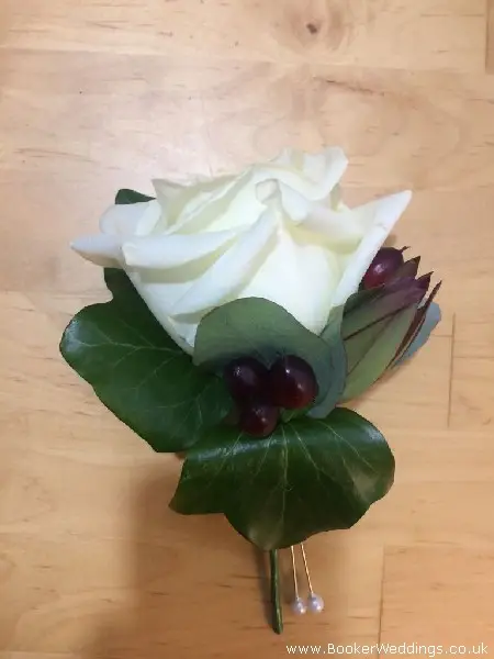 groom white rose buttonhole with hypericum berries and eucadendron