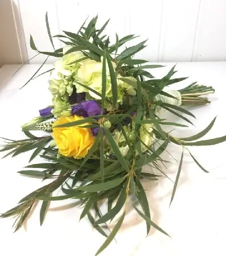 Bridesmaid hand-tied bouquet of just picked yellow and purple roses, lissianthus, ranunculus, hydrangea, veronica, calla lily